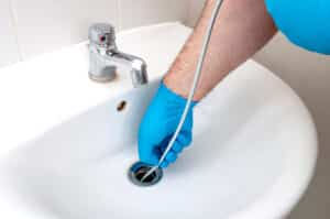 A licensed and insured plumber working on a sink in a bathroom.