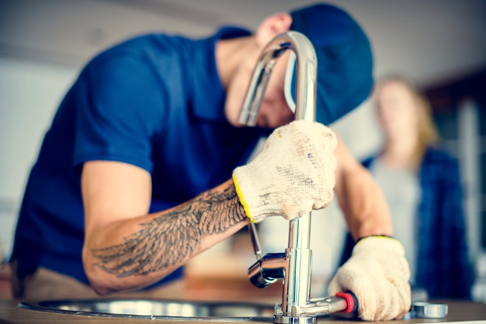 Illustration of a plumber fixing a sink with tools. Represents hiring a professional plumber for plumbing issues.